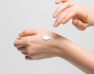 AgelessBeauty3000.com Hand applying cream to another hand on a light gray background