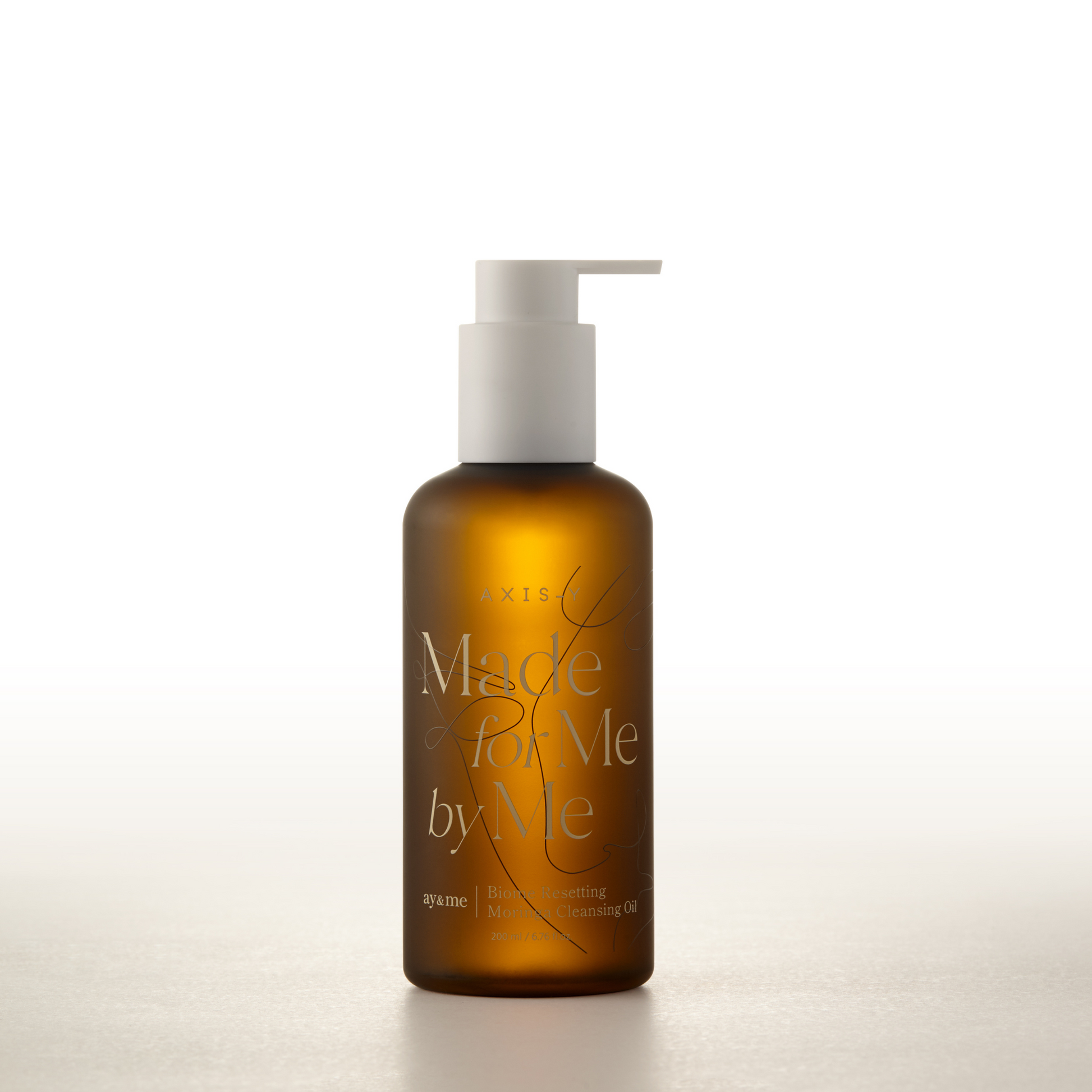 AgelessBeauty3000.com  AXIS-Y  |  Biome Resetting Moringa Cleansing Oil  Brown bottle with pump labeled 'Made by Me' on a white background