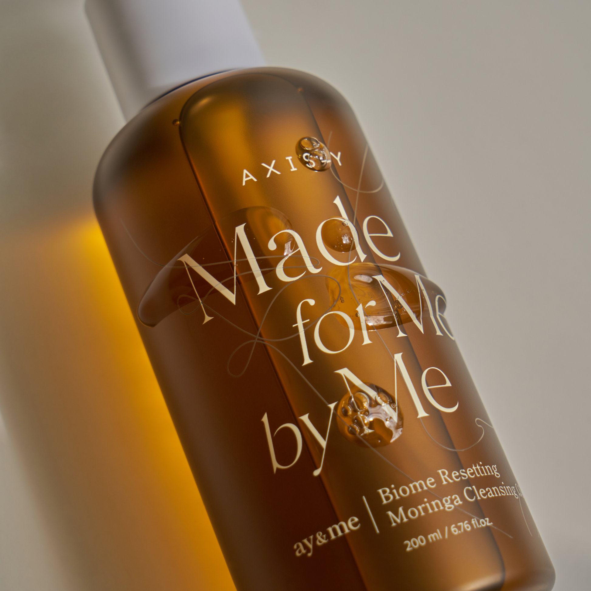 AgelessBeauty3000.com  AXIS-Y  |  Biome Resetting Moringa Cleansing Oil  Bottle of 'Made for Me by Me' skincare product with a gradient background