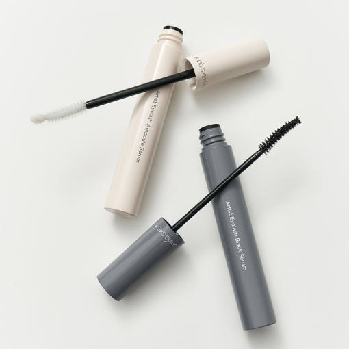 Two mascara tubes, one beige and one gray, on a white background.  AgelessBeauty3000.com  JUNGSAEMMOOL |   Artist Eyelash Serum